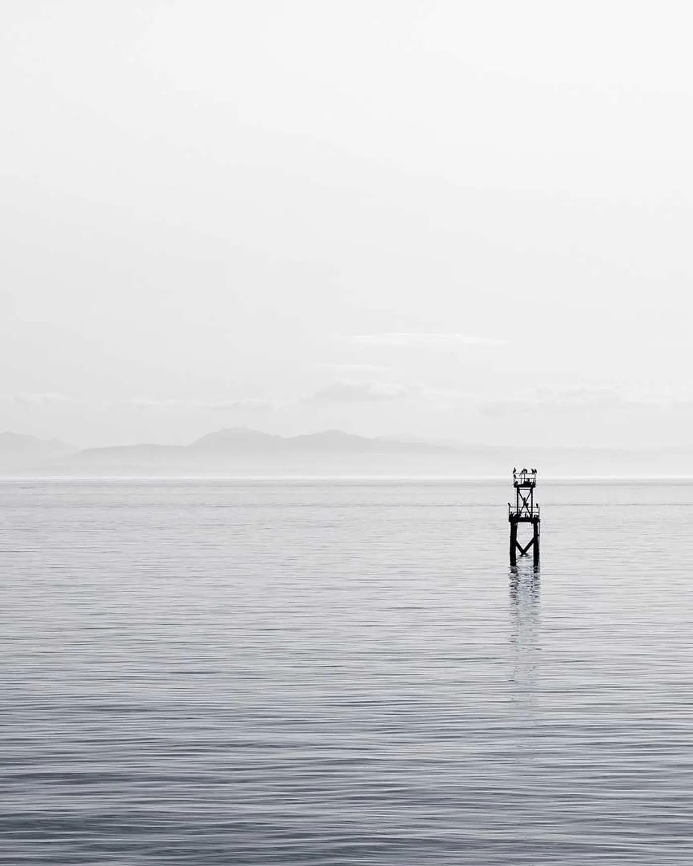 Una baliza solitaria sobre agua quieta y gris